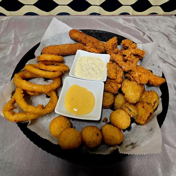 A platter of fried appetizers, including onion rings, mozzarella sticks, chicken tenders, and fried pickles.