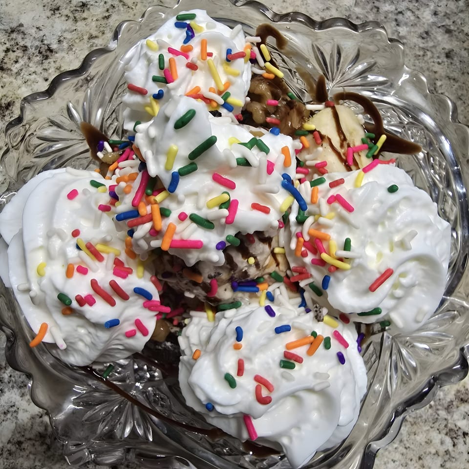 A Woodstock Way Groovey Eatery sundae with whipped cream, colorful sprinkles, and chocolate syrup.